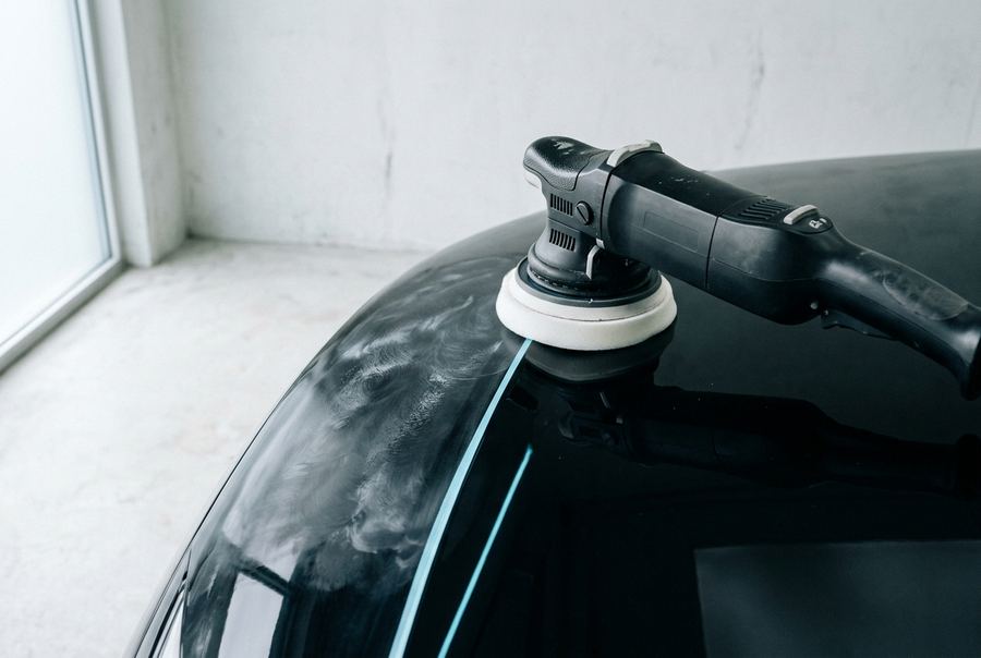 A dual-action polisher correcting a black wing panel